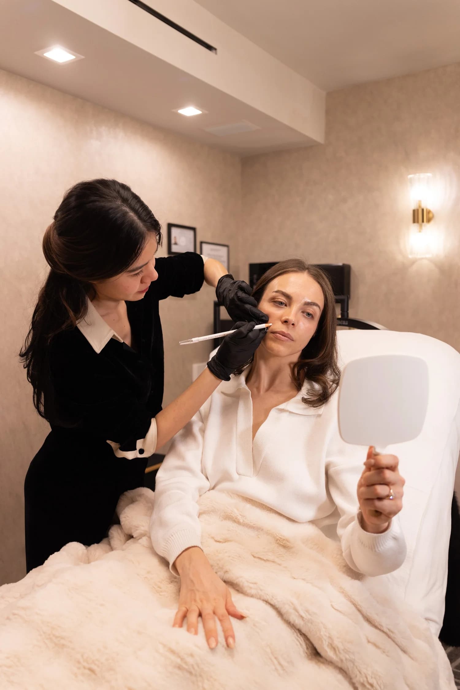 A client reviews her reflection during a needle-free AgeSculpt session at the Manhattan studio.
